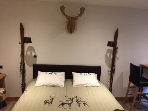 Chambre prestige Aux Pays Des Sucs avec décoration cerf, lit noir et lances décoratives à Saint-Hostien