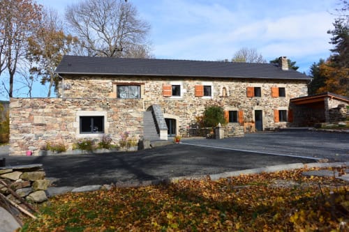 Gîte en pierre aux toits sombres d'Aux Pays Des Sucs à Saint-Hostien, entouré de feuillages d'automne et d'une allée