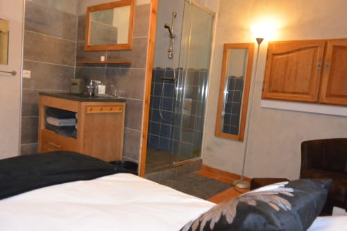 Chambre moderne avec salle de bain attenante au gîte Aux Pays Des Sucs, dotée de lits, coiffeuse, douche et boiseries