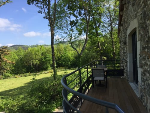 Terrasse en bois courbée avec balustrade métallique surplombant les champs verts et la forêt à Aux Pays Des Sucs, Saint-Hostien