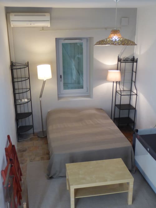 Cozy bedroom in Ramona cottage at Domaine de Lamartine, Pont-Saint-Esprit with bed, shelving, lamps and window
