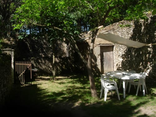 Garden courtyard at Domaine de Lamartine cottage in Pont-Saint-Esprit with shaded dining table and stone walls