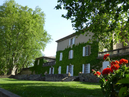 Ivy-covered château at Domaine de Lamartine, Pont-Saint-Esprit, with manicured gardens and red flowers