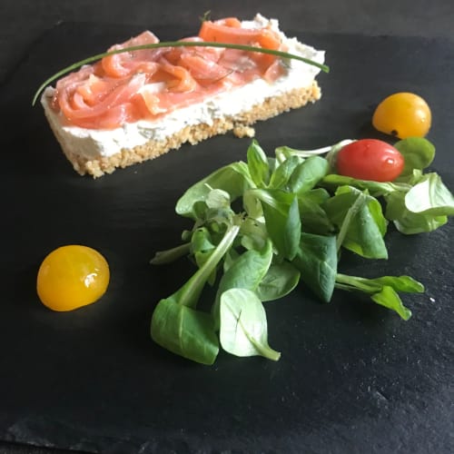 Smoked salmon canapé with cream cheese on rye bread, served with fresh greens and cherry tomatoes at Le Pignié