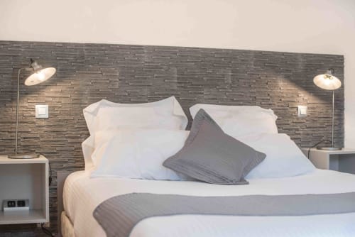 Modernes Schlafzimmer im Le Pignié B&B in Lescure-d'Albigeois mit Steinakzentwand, weißer Bettwäsche und Leselampen