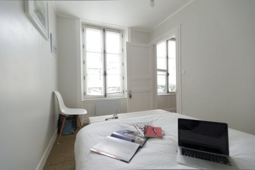 Chambre lumineuse avec lit, ordinateur portable et vue sur Port-en-Bessin à l'hôtel Les Filles du Bord de Mer
