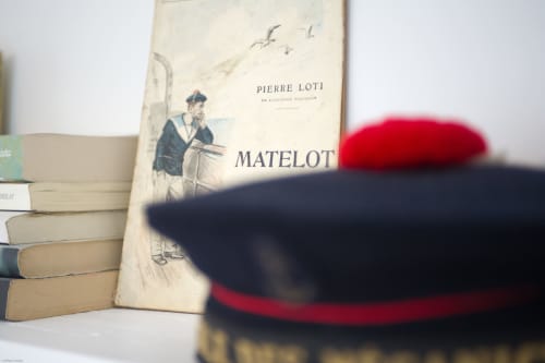 Le roman classique français « Matelot » de Pierre Loti présenté avec des livres anciens et un béret rouge dans un appartement à Port-en-Bessin