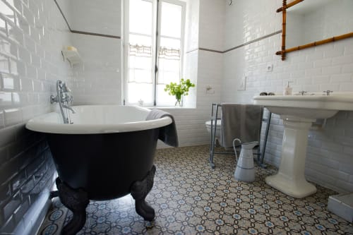 Élégante salle de bain aux Filles du Bord de Mer avec baignoire îlot noire, carrelage blanc et sol à motifs