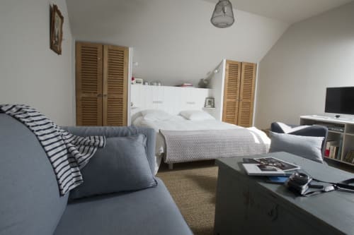 Chambre lumineuse sous les toits aux Filles du Bord de Mer avec lit, canapé, TV, placards en bois et vue sur le port