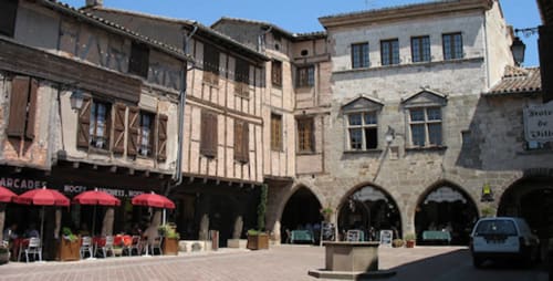 Medieval courtyard at Le Pignié B&B in Lescure-d'Albigeois with historic arcades and red umbrellas