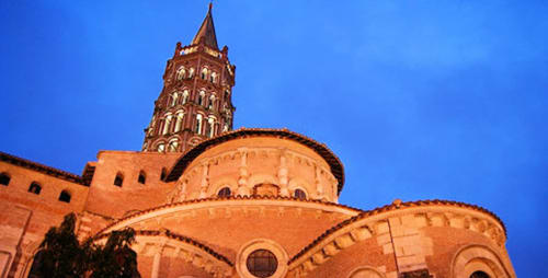 Illuminated brick church tower and dome at dusk in Lescure-d'Albigeois, France near Le Pignié
