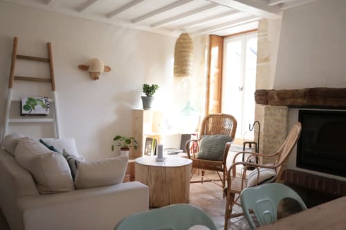 Salon côtier lumineux avec canapé crème, fauteuils en rotin, cheminée et vue sur mer aux Filles du Bord de Mer