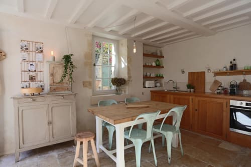 Cuisine lumineuse avec poutres en bois, mobilier blanc, chaises turquoise et table à dîner aux Filles du Bord de Mer