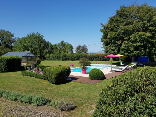 Zone piscine du Domaine de La Serita avec transats, parasols, jardins paysagés et serre à Joze, France