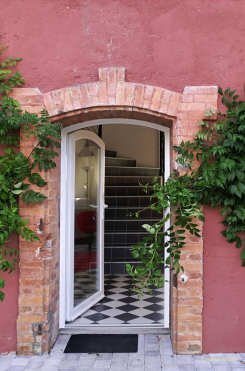 Entrée en arche de briques du Domaine de La Serita B&B à Joze, France avec lierre et vestibule aux carrelages noir et blanc