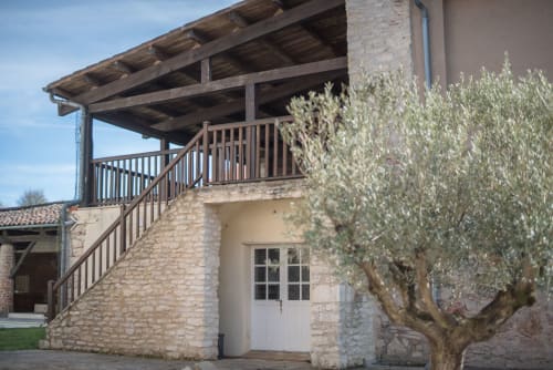 Stone cottage at Le Pignié with wooden deck, olive tree, and garden view in Lescure-d'Albigeois