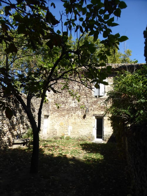 Stone cottage at Domaine de Lamartine with shaded garden featuring grapevine in Pont-Saint-Esprit