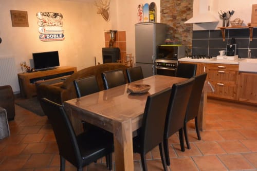 Espace ouvert cuisine-salle à manger du Gîte Aux Pays Des Sucs, Saint-Hostien avec table en bois, chaises noires et design moderne