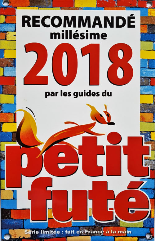 Panneau de recommandation du guide touristique Petit Futé 2018 fixé sur un mur de briques colorées au Domaine de La Serita, JOZE France