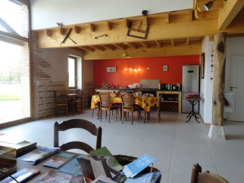 Spacieuse salle à manger de la Ferme Passion BnB avec mur d'accent rouge, poutres en bois apparent et cuisine moderne