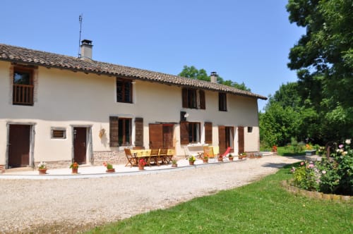 Maison d'hôtes Ferme Passion avec façade crème, volets en bois et coin détente dans la cour