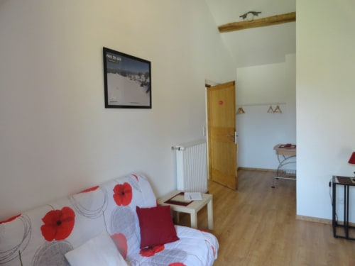 Chambre douillette à la Ferme Passion B&B avec canapé motif coquelicots, poutres bois et charme champêtre