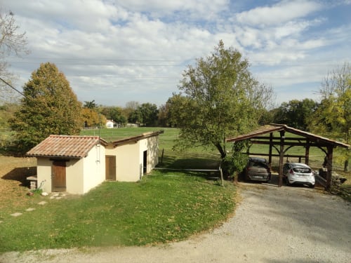 Ferme Passion B&B avec maison de ferme crème, toit en tuiles rouges, abri voitures en bois et pâturages verts
