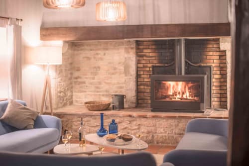 Cozy cottage sitting area at Le Pignié with fireplace, gray seating, and wine service in Lescure-d'Albigeois