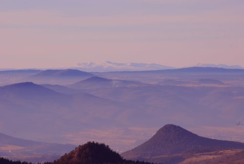 Chaînes de montagnes et vallées étagées au lever du soleil à Saint-Hostien, France, avec pics enneigés à l'horizon