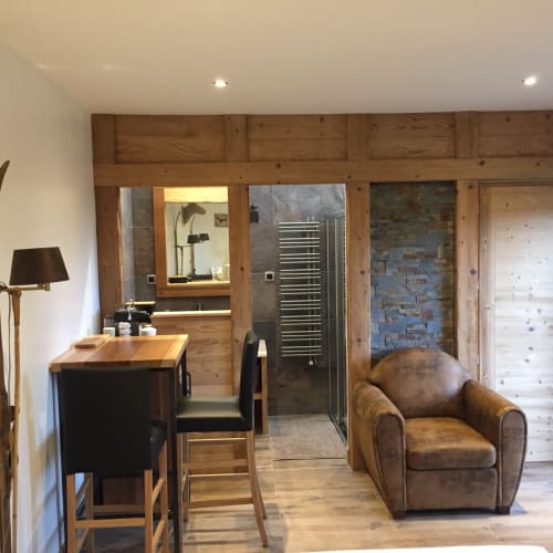 Coin salon rustique avec fauteuil en cuir, bureau et poutres en bois aux Pays Des Sucs