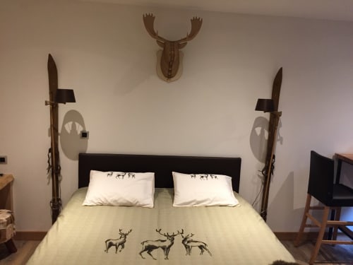 Chambre aux Pays des Sucs avec décor aux cerfs, tête de lit noire, literie blanche et épées décoratives