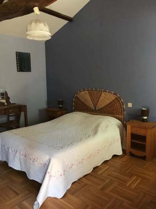 Chambre cosy de la Chambre d'hôtes La Raymondiere à Vernoux-en-Gâtine avec tête de lit en osier et literie crème