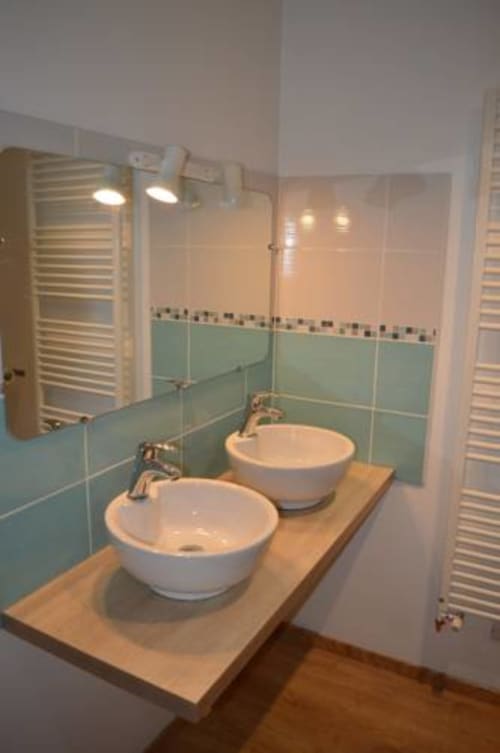 Salle de bains moderne à la Chambre Dombes du Ferme Passion BnB avec vasques blanches doubles, carrelage bleu clair, porte-serviettes chauffants