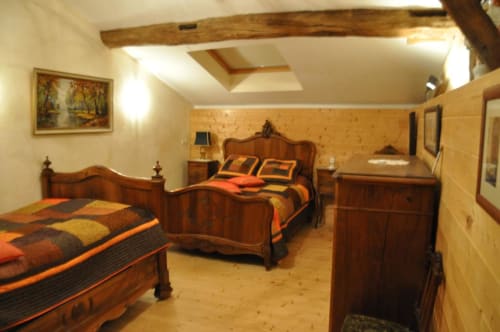 Chambre rustique à Ferme Passion avec deux lits en bois, literie orange, poutres apparentes et décor traditionnel de campagne française