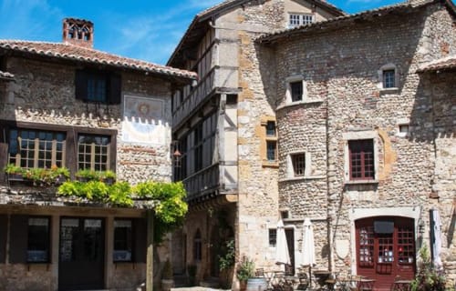 Cour de la Ferme Passion B&B à Saint-Trivier-sur-Moignans avec bâtisses en pierre rustique et balcon recouvert de lierre