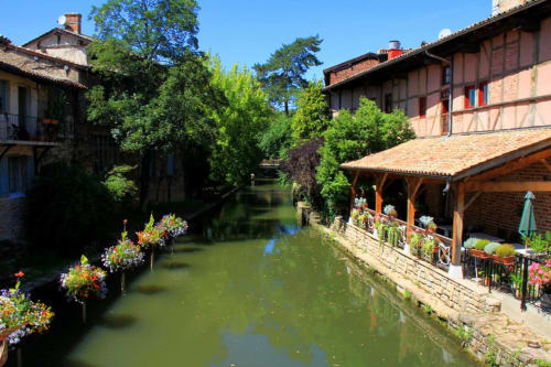 Ferme Passion B&B à Saint-Trivier-sur-Moignans avec canal, bâtiments historiques, fleurs et terrasse au bord de l'eau