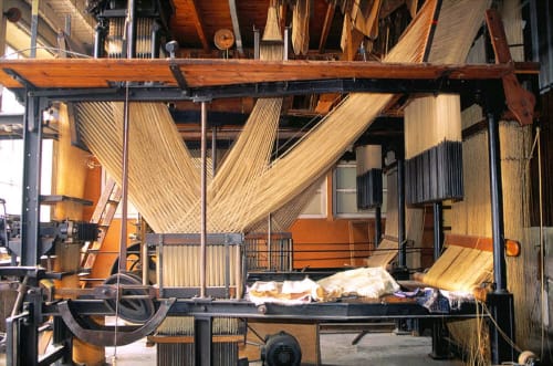 Intérieur rustique d'une grange à Ferme Passion avec poutres en bois, panneaux de tôle ondulée et équipements agricoles