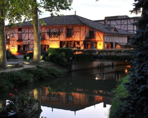 Le bâtiment à colombages illuminé de la Ferme Passion BnB se reflétant dans l'étang au crépuscule, Saint-Trivier-sur-Moignans