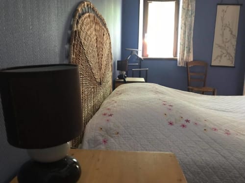 Chambre double accueillante à La Raymondière avec tête de lit en rotin, couvre-lit fleuri et vue sur le jardin à Vernoux-en-Gâtine