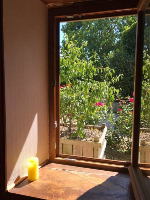 Porte vitrée ouverte de la Chambre Triple à La Raymondière B&B à Vernoux-en-Gâtine, vue sur le jardin fleuri luxuriant