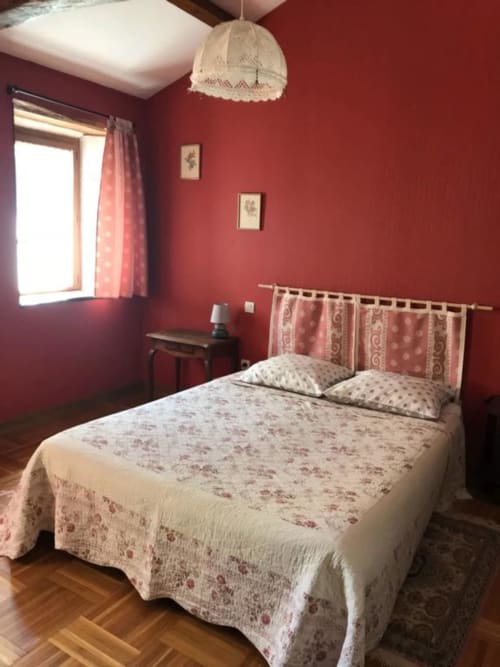 Chambre triple accueillante à La Raymondière avec murs rouges, applique en dentelle et literie fleurie