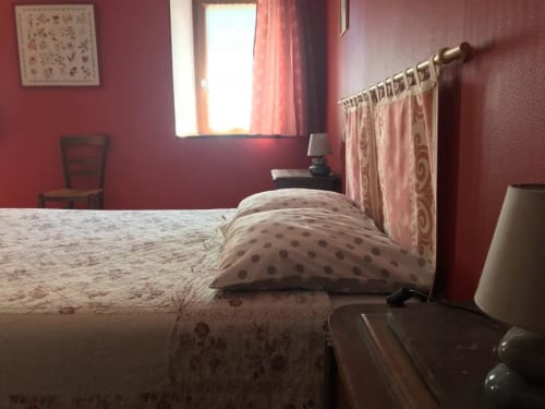 Chambre triple de la Maison d'hôtes La Raymondière à Vernoux-en-Gâtine avec murs bordeaux et vue sur le jardin