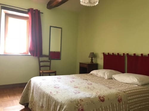 Chambre spacieuse du gîte La Raymondière à Vernoux-en-Gâtine avec vue sur le jardin, tête de lit bordeaux, literie crème et touches de tilleul