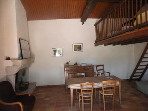 Séjour de la maison à La Raymondière avec table en bois, cheminée et mezzanine à Vernoux-en-Gâtine
