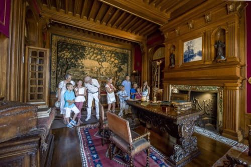 Ornate wooden room with tapestry, fireplace, and visitors at Château De Clusors B&B in Saint-Menoux, France