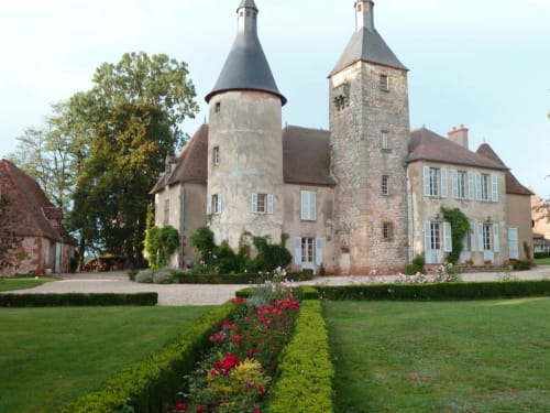 Château de Clusors, un encantador castillo francés con torretas y torres de piedra en jardines bien cuidados en Saint-Menoux, Francia.