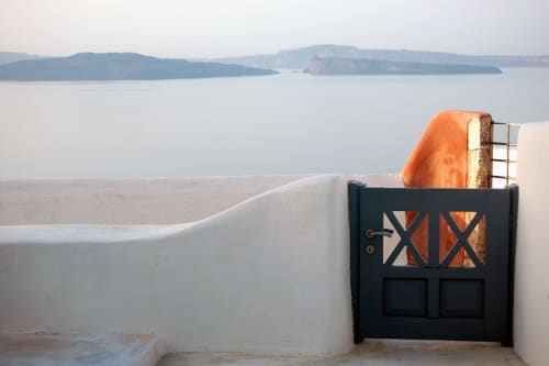Puerta negra con tejado naranja frente a la caldera de Santorini e islas, vistas al mar del Hotel Santorini