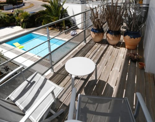 Terrasse balcon de Côte Et Dune Biscarrosse avec vue sur la piscine, table blanche, chaises longues et plantes en pots