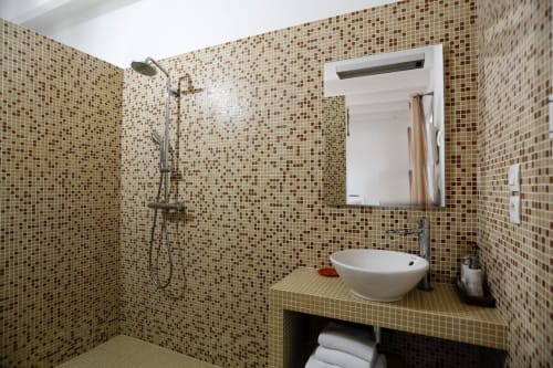 Salle de bain moderne avec carrelage mosaïque marron, vasque ronde, miroir et pomme de douche pluie à l'hôtel Côte et Dune