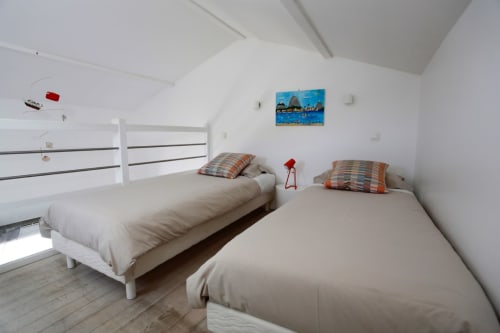 Chambre mezzanine lumineuse à Côte Et Dune avec deux lits simples, oreillers rayés, murs blancs et décoration côtière à Biscarrosse